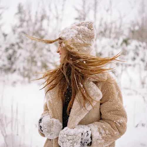 Frau in schützender Winterkleidung bei Schnee für Haare im Winter Tipps von Ellas Haar Shop